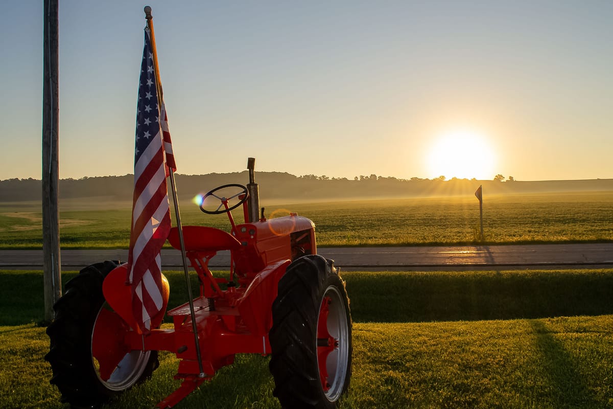 Red tractor with an American flag at sundown